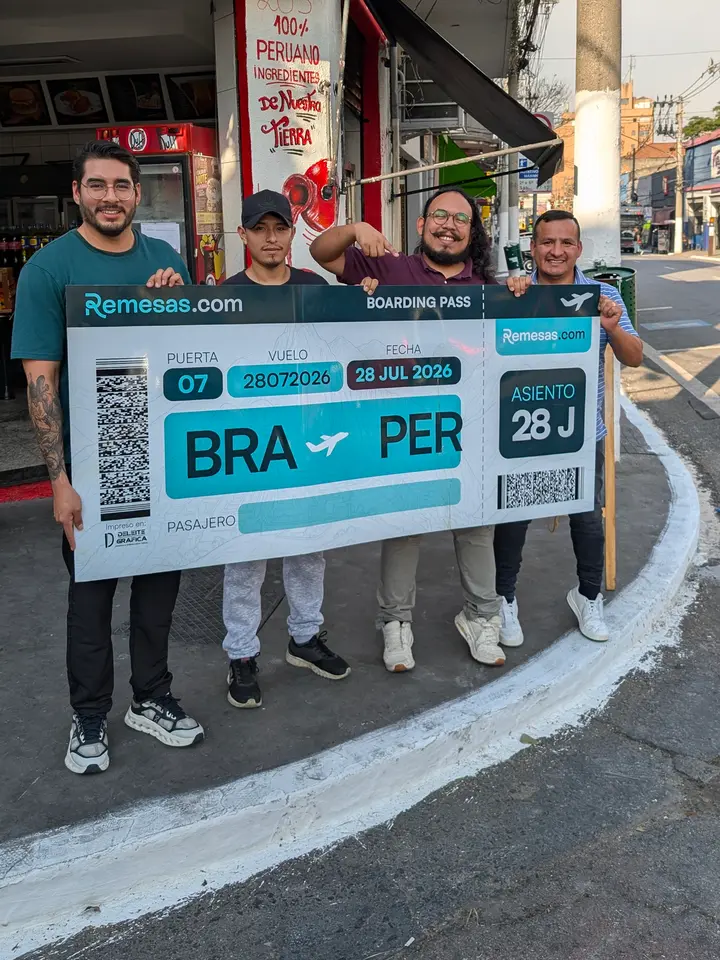 Parte del equipo de Remesas.com con un boarding pass gigante Brasil–Perú en una calle de São Paulo