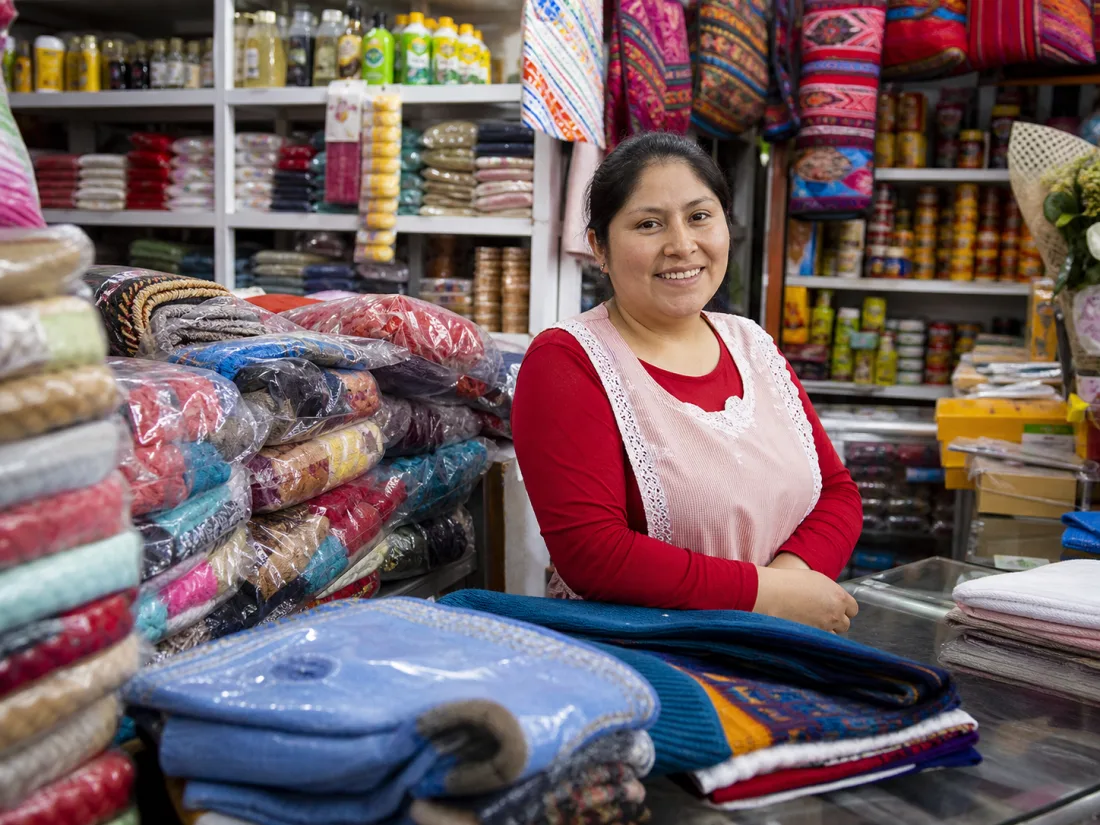Comerciante peruana atendiendo en su tienda de textiles en un mercado
